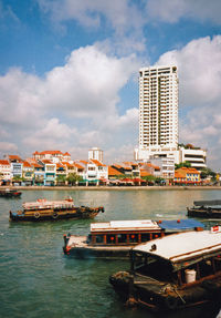 Boats moored at harbor against buildings in city