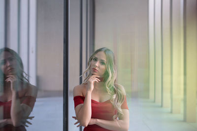 Woman looking away while sitting on window