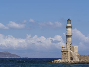 Lighthouse at old venetian harbour in sea against sky