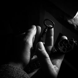 Cropped hands holding old keys in darkroom