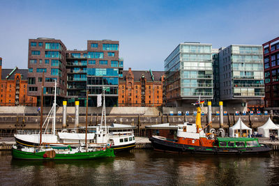 Sailboats moored in river against buildings in city