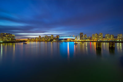 Scenic view of lake by illuminated buildings against sky at night