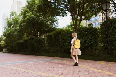 Full length portrait of woman standing against trees