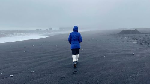 Rear view of woman walking at black sand beach in iceland