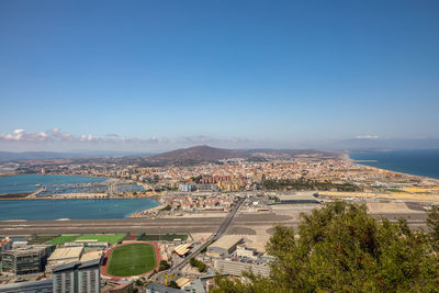 High angle view of townscape by sea against clear sky