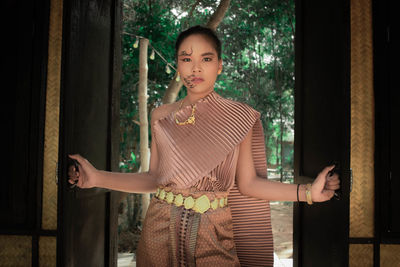 Portrait of woman with face paint in traditional clothing standing at doorway