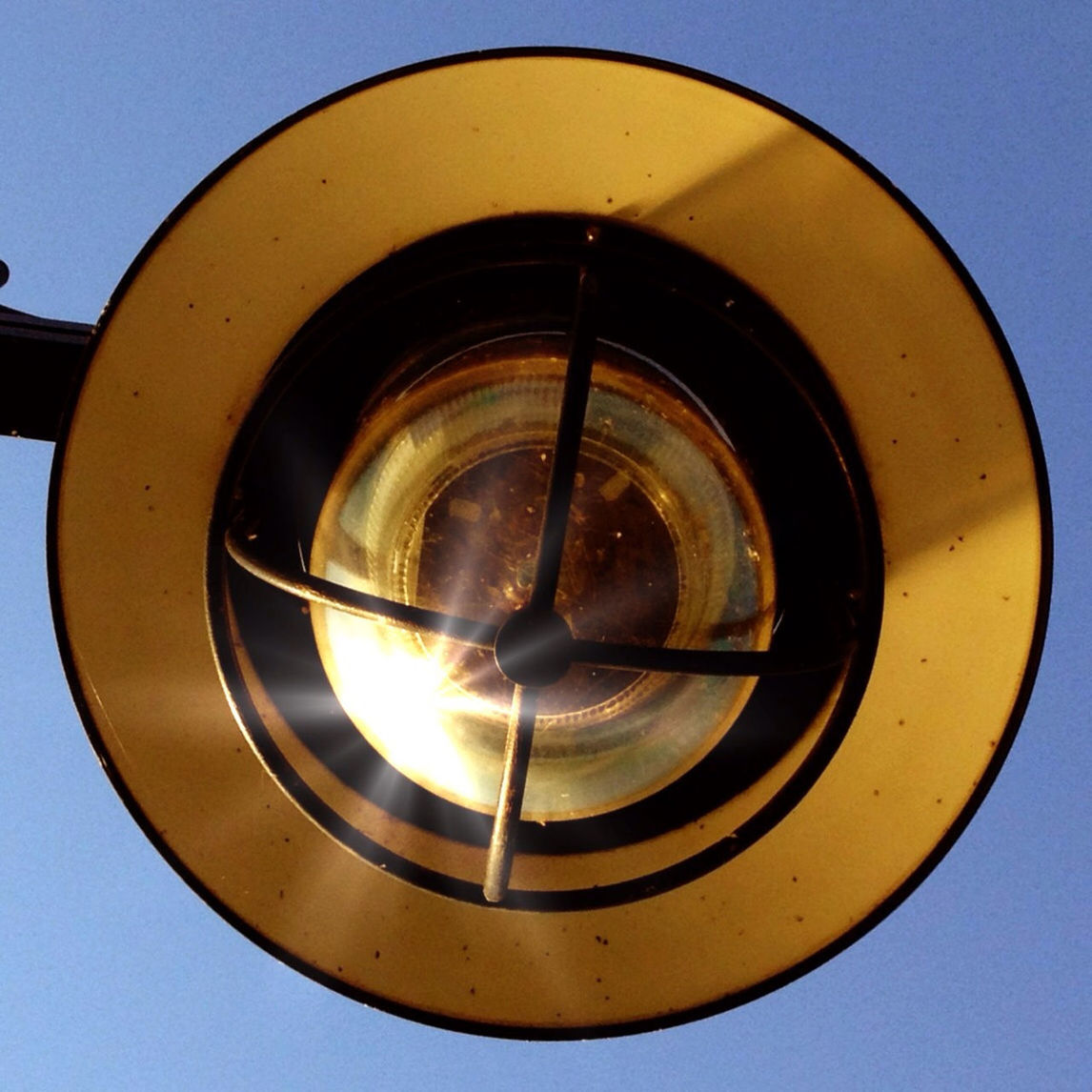 close-up, low angle view, lighting equipment, circle, electricity, metal, indoors, light bulb, no people, illuminated, glass - material, glowing, electric light, single object, yellow, clear sky, copy space, transparent, sky, technology