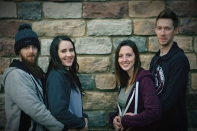 Portrait of smiling young couple standing against wall