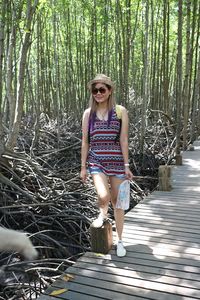 Full length of woman standing on boardwalk in forest