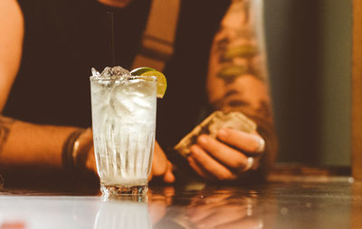 Midsection of man with cocktail sitting at table