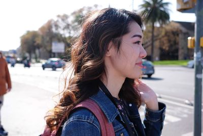 Portrait of young woman looking away on street in city