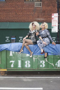 Two drag queens sitting on a skip