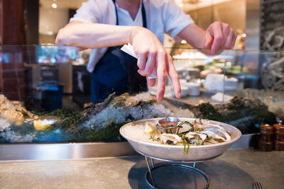 Midsection of man hand over oysters on table at restaurant