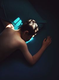 High angle view of shirtless teenage boy sleeping on bed
