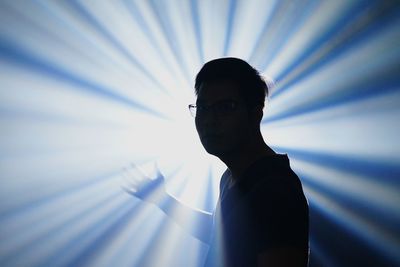 Young man standing against light beams