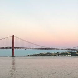 Suspension bridge over river against sky during sunset