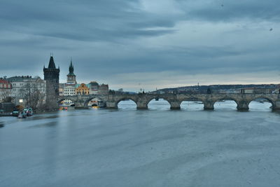 Arch bridge over river against cloudy sky