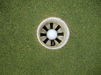 Directly above view of white golf ball in hole on course
