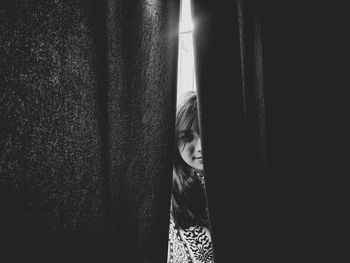 Close-up of a girl standing against window