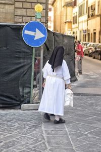 Rear view of woman walking on street amidst buildings