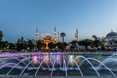 Fountain in city against clear sky