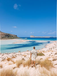 Rear view of man standing on beach against sky