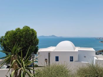 Built structure by sea against clear blue sky