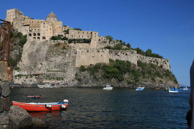 Sailboats moored on sea against buildings