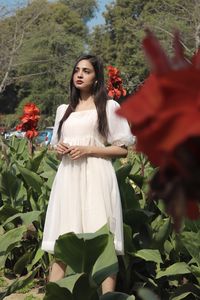 Portrait of young woman standing by plants