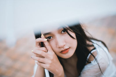 Portrait of young woman with umbrella sitting outdoors