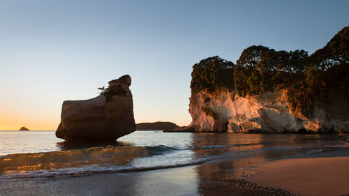 Rock formation on sea against sky during sunset