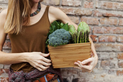 Woman holding basket with fresh vegetables