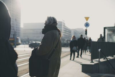 Woman walking in city against clear sky