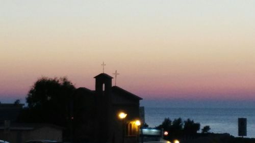 Illuminated building against sky at sunset