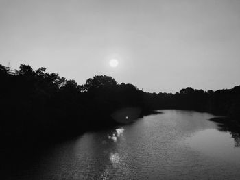 Scenic view of river amidst silhouette trees against sky