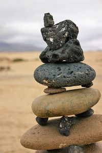 Stack of pebbles on shore against sky