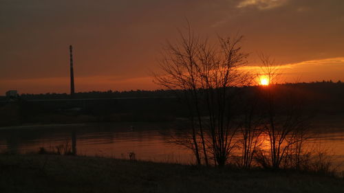 Silhouette trees by lake against sky during sunset