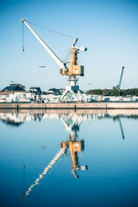 Cranes at commercial dock against clear blue sky