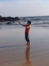 Full length of boy on beach against sky