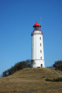 Lighthouse on landscape against clear blue sky