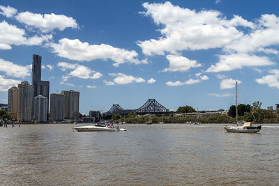 Sailboats in river against buildings in city