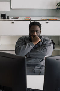 Male entrepreneur with hand on chin sitting at office