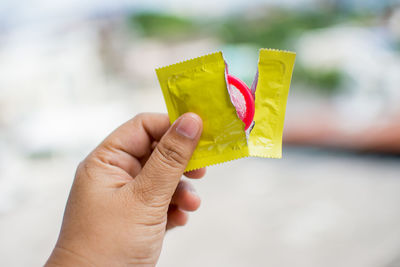 Close-up of man holding condom outdoors