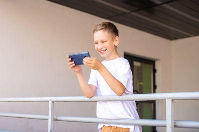 A child holds a phone in his hands near the school