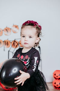 Cute girl holding balloon during halloween at home