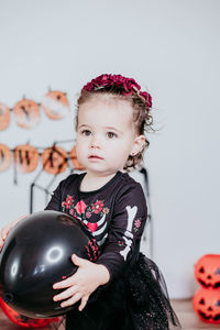 Portrait of cute baby girl sitting on bed at home