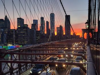 Illuminated street amidst buildings against sky during sunset