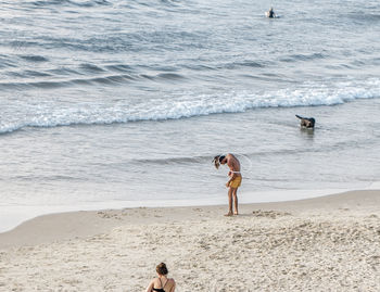 Woman with dog standing on beach