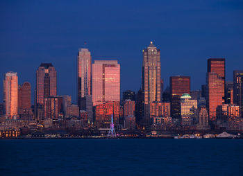 Illuminated buildings in city against blue sky