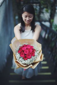 Close-up of smiling young woman holding red flower